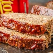 The image shows two slices of Stove Top stuffing meatloaf placed on a wooden board. In the background, there is a box of Stove Top stuffing mix.