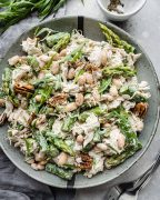 Tarragon Chicken Salad in a grey bowl: Shredded chicken mixed with asparagus, beans, nuts, and tarragon leaves, coated in a creamy dressing.
