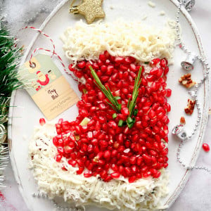 A festive Christmas Chicken Salad arranged in the shape of a stocking on a white plate. The salad features diced chicken, pecans, celery, mozzarella cheese, green onions, and pomegranate arils, and mayo dressing.