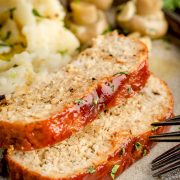 Plate of delicious turkey meatloaf slices served with creamy mashed potatoes and tangy marinated mushrooms.
