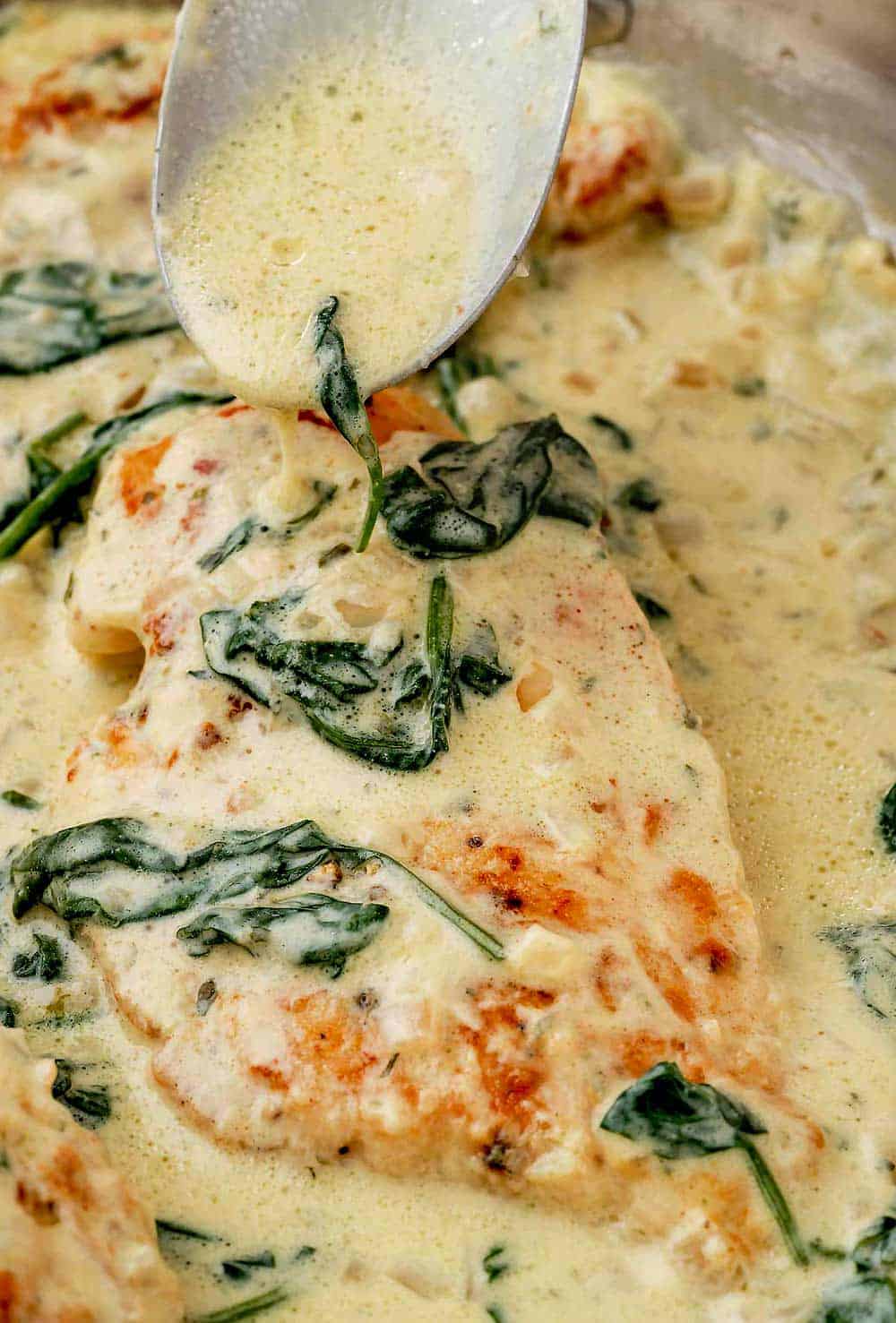 Pouring Boursin cheese sauce over Creamy Boursin Chicken in a skillet.