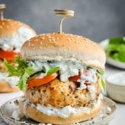 Juicy turkey burger topped with creamy tzatziki sauce, lettuce, tomato on a burger bun.