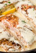 Baked salmon fillets smothered in creamy Boursin cheese sauce in a skillet.