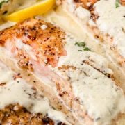 Baked salmon fillets smothered in creamy Boursin cheese sauce in a skillet.