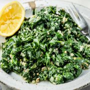 Sautéed Spinach with Garlic and Parmesan served on a white plate with a fork.