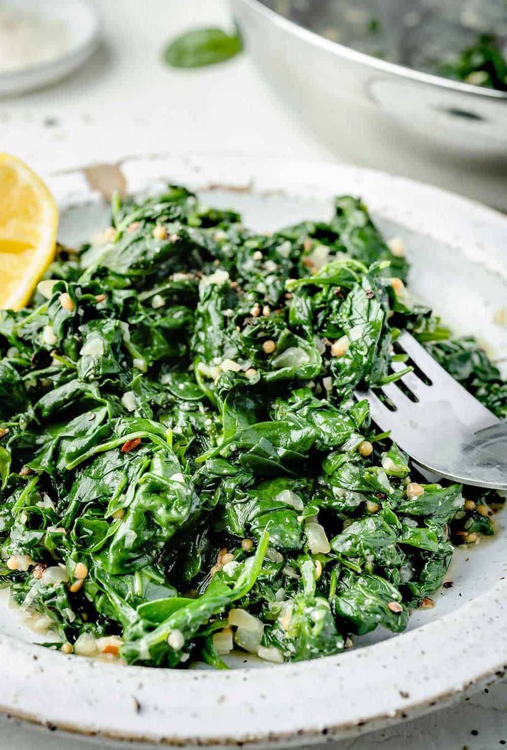 Sautéed Spinach with Garlic and Parmesan served on a white plate with a fork.