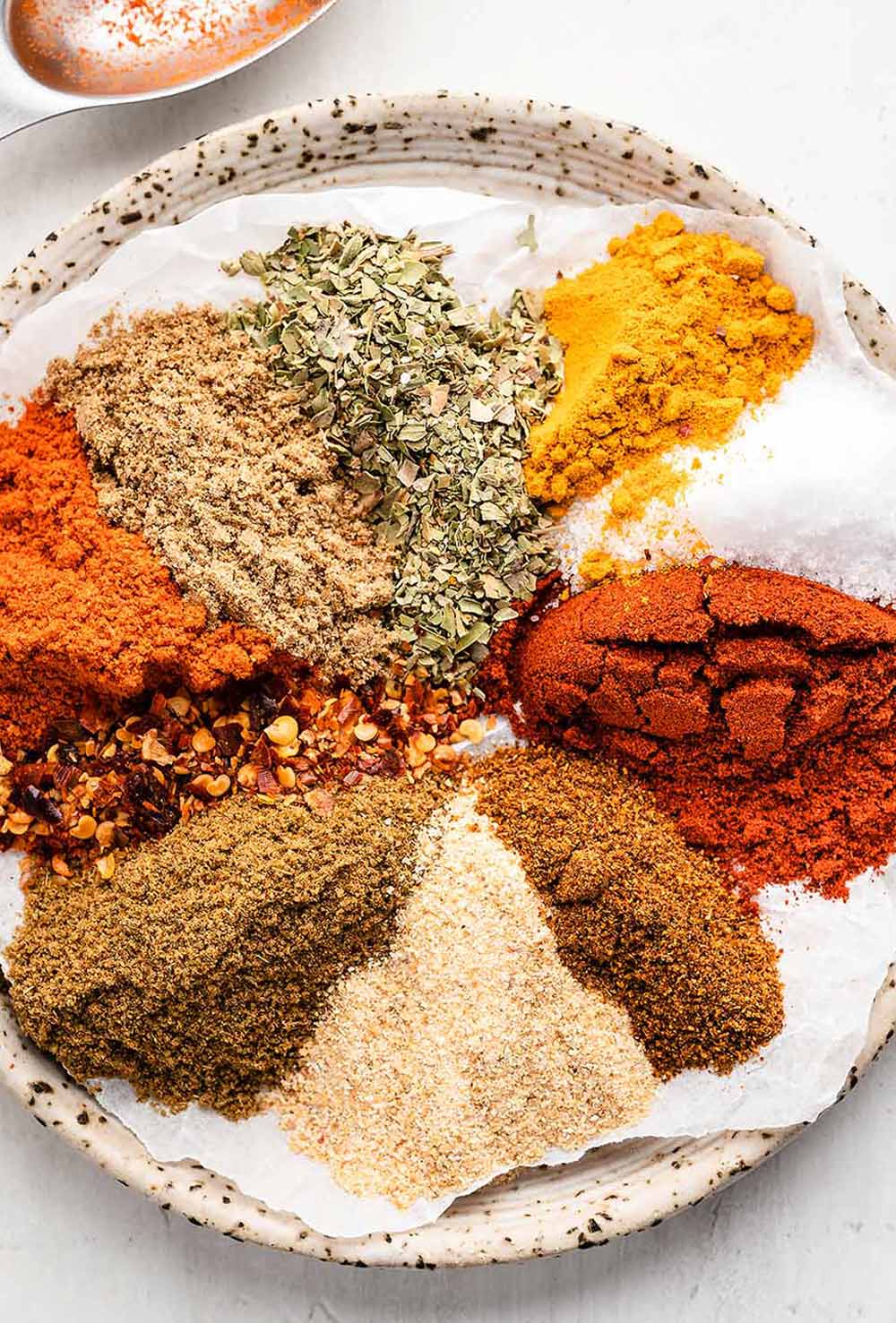 Assorted spices on a plate, ready to be mixed for Homemade Southwest Seasoning.