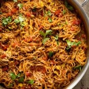 Steaming skillet of homemade taco spaghetti with ground beef, melted cheese, and spaghetti noodles, garnished with fresh cilantro.