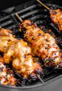 Chicken skewers cooked in an air fryer basket, golden and sizzling, with a glimpse of the crispy exterior.