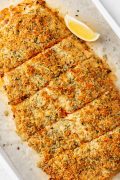 Image of a golden Baked Parmesan Crusted Salmon fillet with Mayo on a baking sheet.