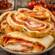 Sliced stromboli with visible fillings, neatly arranged on a plate, showcasing its golden brown crust and mouthwatering inner layers.