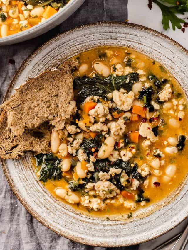 A bowl of hearty ground turkey soup with a side of fresh bread.