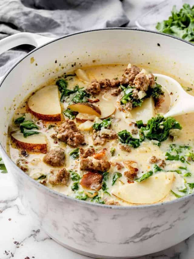 Image of Zuppa Toscana Soup in a Dutch oven. The soup is creamy and abundant with Italian sausage, potato slices, and kale, showcasing a variety of colors and textures.
