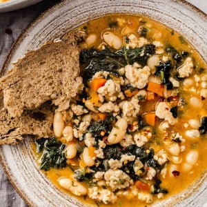 A bowl of hearty ground turkey soup with a side of fresh bread.