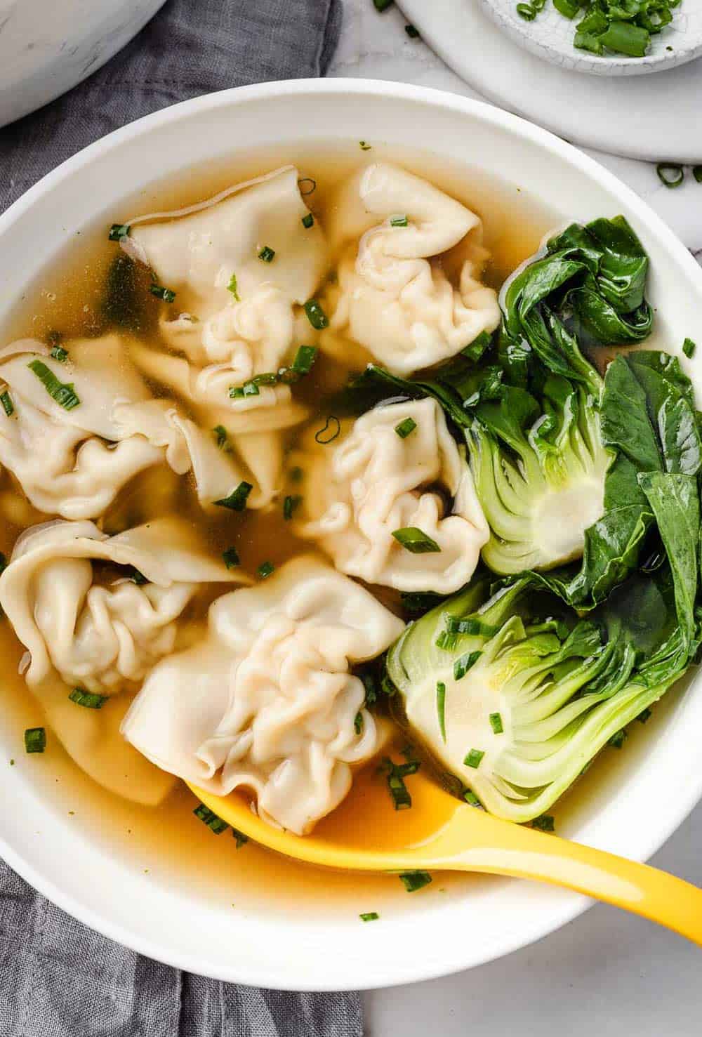 Overhead image of Wonton Soup in a white bowl, featuring plump wontons and fresh bok choy in a clear, flavorful broth.