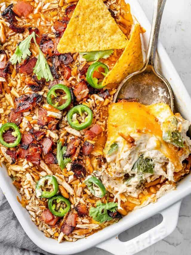 Image showing a freshly baked Jalapeño Popper Chicken Casserole in a baking dish. The casserole is golden and bubbly on top, with visible pieces of jalapeño, chicken, and melted cheese.