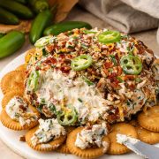 Image of a jalapeno popper cheese ball on a serving board, surrounded by crackers.