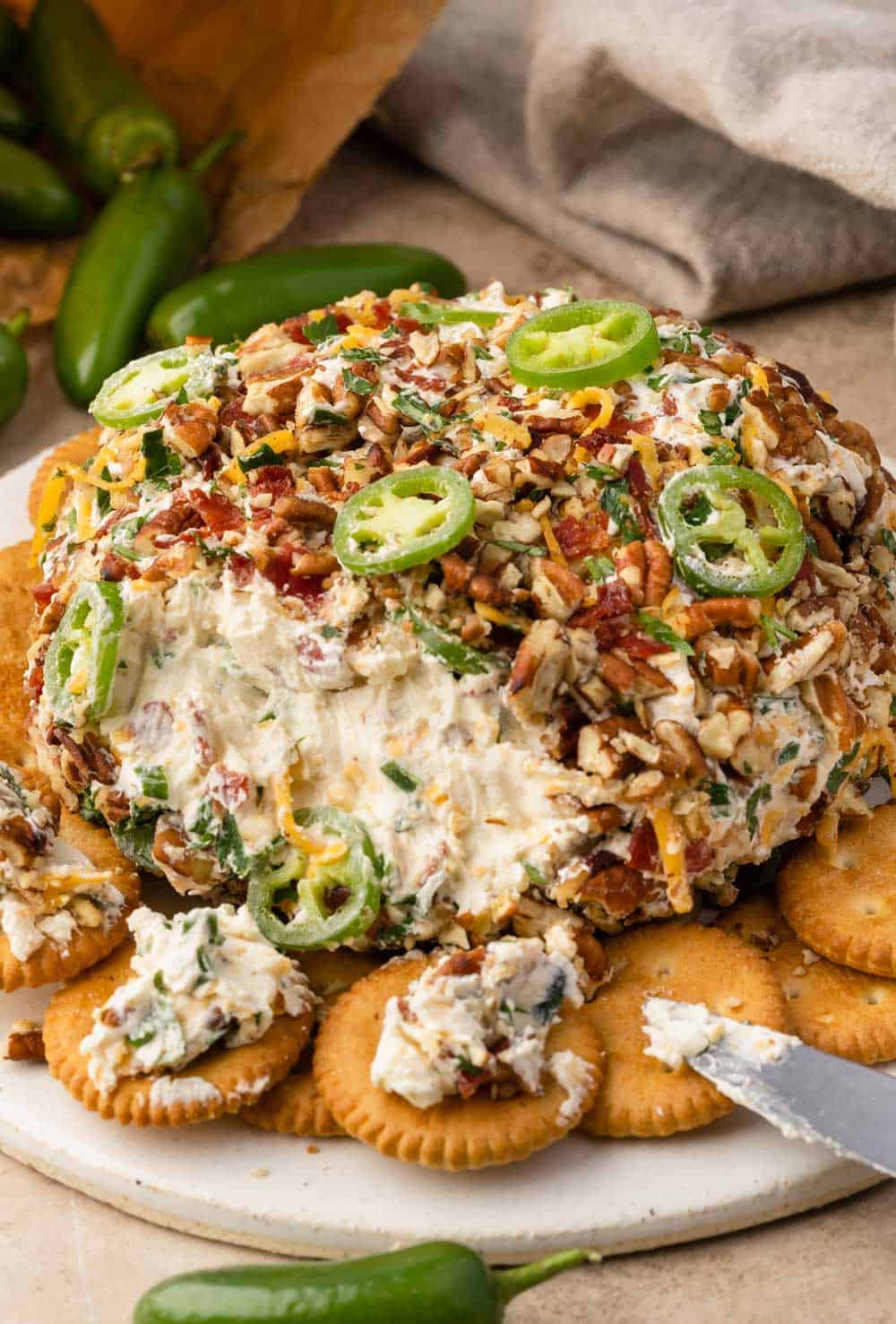 Image of a jalapeno popper cheese ball on a serving board, surrounded by crackers.