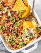 Image showing a freshly baked Jalapeño Popper Chicken Casserole in a baking dish. The casserole is golden and bubbly on top, with visible pieces of jalapeño, chicken, and melted cheese.