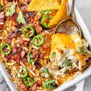 Image showing a freshly baked Jalapeño Popper Chicken Casserole in a baking dish. The casserole is golden and bubbly on top, with visible pieces of jalapeño, chicken, and melted cheese.