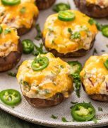 Plate of Jalapeno Popper Stuffed Mushrooms with a creamy cheese filling and jalapeno garnish.