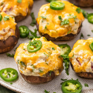 Plate of Jalapeno Popper Stuffed Mushrooms with a creamy cheese filling and jalapeno garnish.