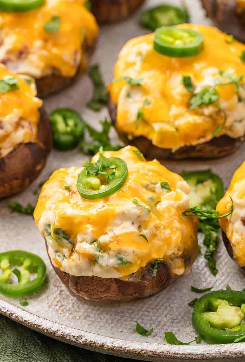 Plate of Jalapeno Popper Stuffed Mushrooms with a creamy cheese filling and jalapeno garnish.