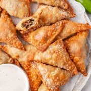 Overhead view of a plate containing Air fryer Jalapeno Popper Wontons, neatly arranged and served alongside a small bowl of ranch dressing for dipping.