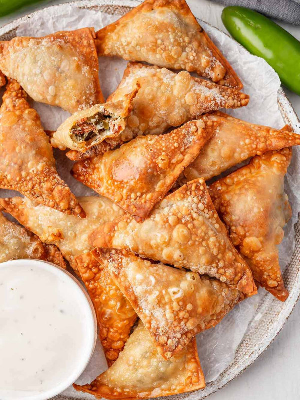 Overhead view of a plate containing Air fryer Jalapeno Popper Wontons, neatly arranged and served alongside a small bowl of ranch dressing for dipping.