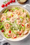 Olive Garden Shrimp Scampi pasta in a skillet, featuring plump shrimp nestled among angel hair pasta, all coated in a rich, garlicky butter and wine sauce.