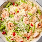 Olive Garden Shrimp Scampi pasta in a skillet, featuring plump shrimp nestled among angel hair pasta, all coated in a rich, garlicky butter and wine sauce.
