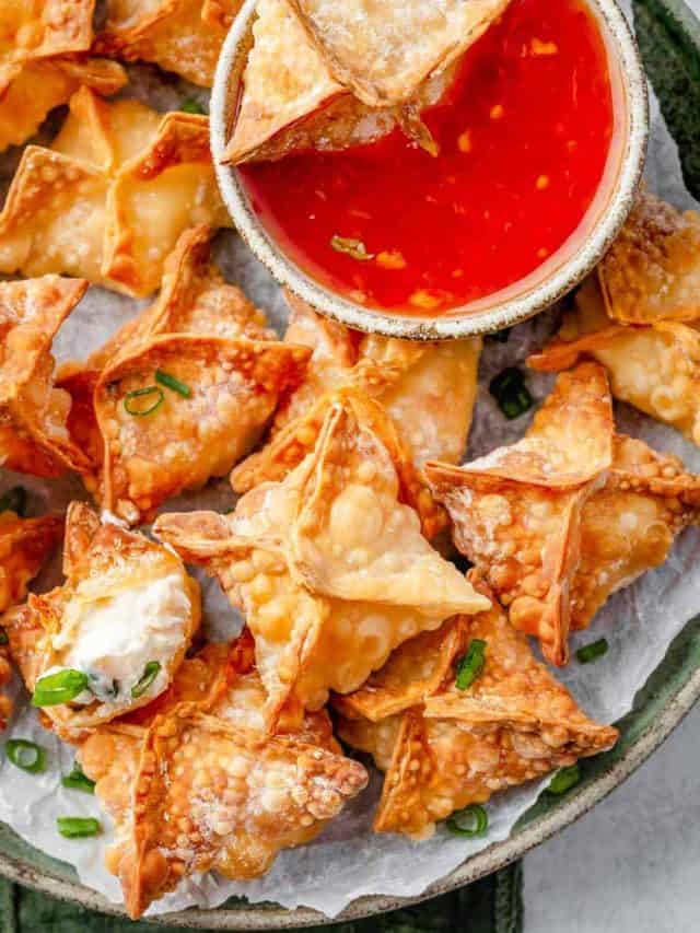 Plate of crispy Shrimp Rangoon served with a side of sweet chili sauce, garnished with fresh green onions.