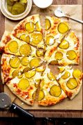 Overhead image of sliced Dill Pickle Pizza, showcasing the unique combination of pickles, cheese, and sauce on a crispy crust.
