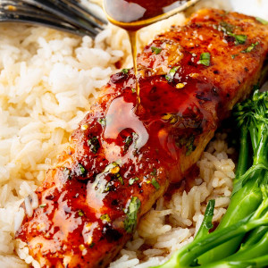 An image showcasing a plate with a hot honey salmon fillet, with hot honey sauce being poured over it, adding a glossy finish.
