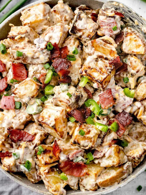 Overhead view of a bowl filled with Jalapeno Popper Potato Salad and garnished with crispy bacon and green onions.