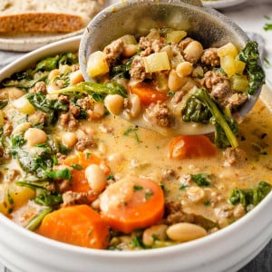 Pouring Tuscan White Bean Soup from a ladle into a bowl.