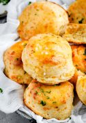 A basket filled with warm Buttermilk Cheddar Biscuits, golden and flaky, ready to be enjoyed at any meal.