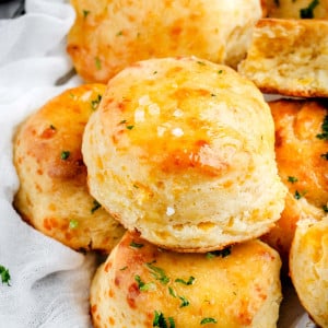 A basket filled with warm Buttermilk Cheddar Biscuits, golden and flaky, ready to be enjoyed at any meal.