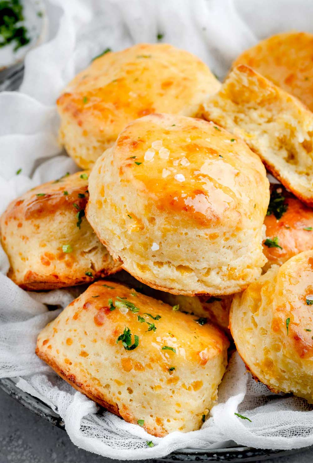 A basket filled with warm Buttermilk Cheddar Biscuits, golden and flaky, ready to be enjoyed at any meal.
