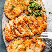 Overhead image of Baked Ranch Chicken served on an oval plate, showing golden-brown, crispy-coated chicken fillets garnished with fresh herbs.