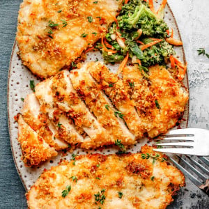 Overhead image of Baked Ranch Chicken served on an oval plate, showing golden-brown, crispy-coated chicken fillets garnished with fresh herbs.