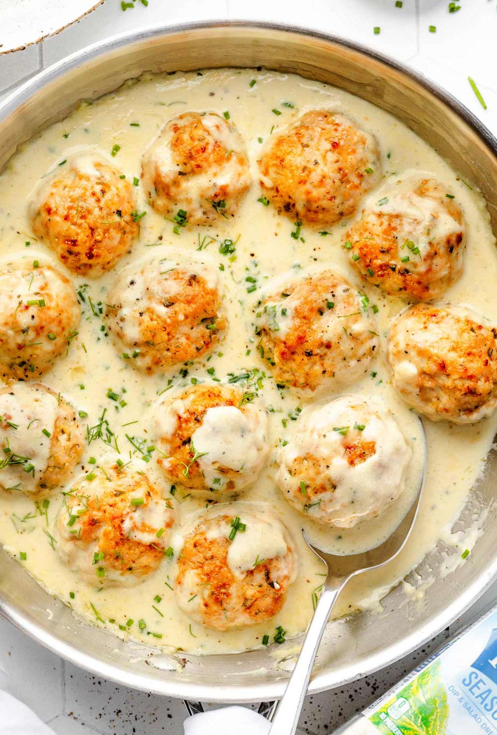 Overhead view of a skillet filled with baked ranch chicken meatballs covered in creamy ranch sauce.