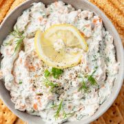 The overhead image of bowl filled with creamy smoked salmon dip, garnished with thinly sliced lemon rounds and sprigs of fresh dill.