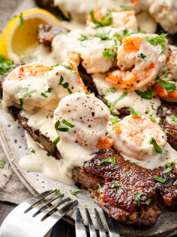 Close-up image of a juicy steak paired with creamy shrimp, served on a plate.