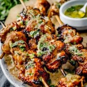 Cooked honey garlic chicken skewers on a plate served with honey garlic butter.