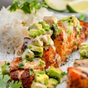 Close-up image of an Air Fryer Hasselback Salmon fillet on a plate, drizzled with spicy sriracha sauce and topped with salsa.