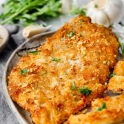 Close-up image of a crispy garlic butter chicken cutlet highlighting the golden, crunchy breadcrumb coating and the rich, buttery glaze.