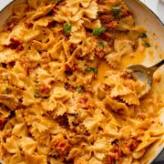A skillet filled with Caramelized Onion Pasta, featuring golden-brown onions, sun-dried tomatoes, fresh basil, and a creamy sauce, ready to be served.