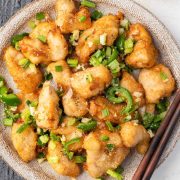 Crispy Salt and Pepper Chicken with vibrant chili and green onion garnish on the plate.