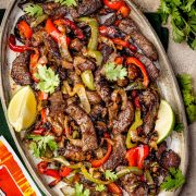 Overhead view of sizzling air fryer steak fajitas served on a plate, featuring juicy strips of seasoned steak, colorful bell peppers, and onions, all garnished with fresh cilantro.